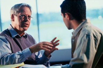 a young male college student talking with his professor