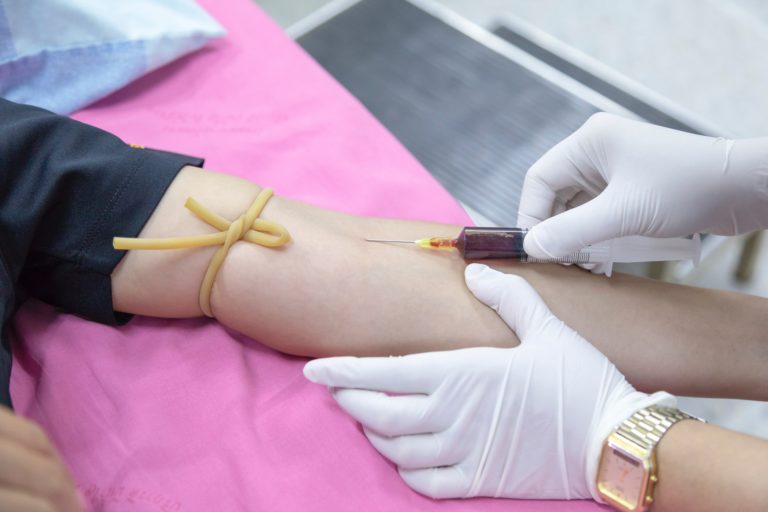 a phlebotomist drawing blood from a patient